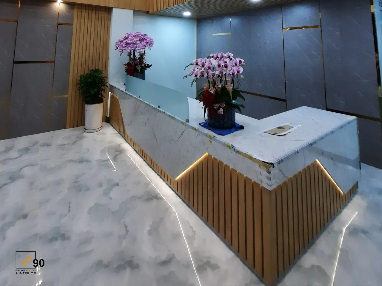 Quầy lễ tân văn phòng được thi công với đá trắng vân mây và lam gỗ trang trí hiện đại tại TP.HCM